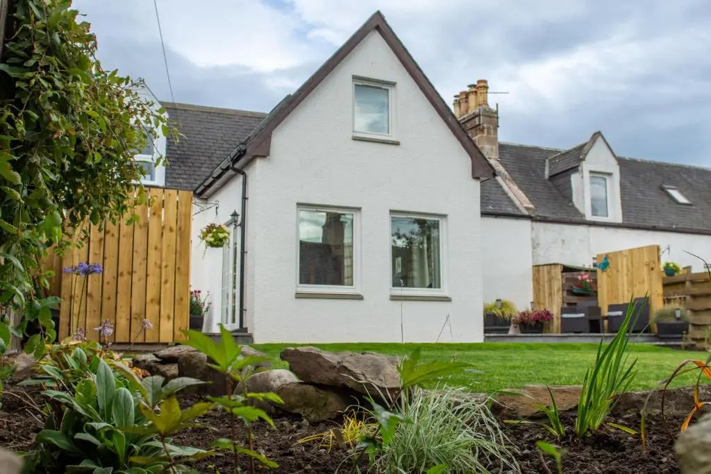 a white house with a fence and a yard at Stunning Country Cottage in Ardross Close To Traitors Castle & NC500 in Boath