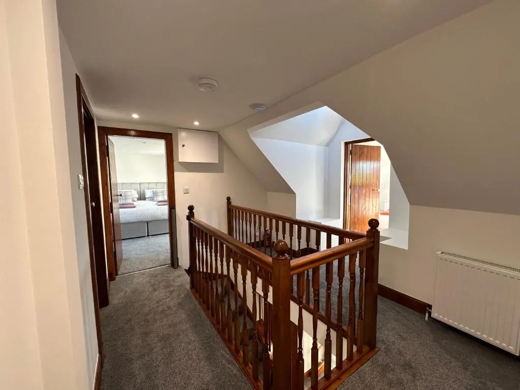 a hallway with a wooden staircase with a mirror at Stunning Country Cottage in Ardross Close To Traitors Castle & NC500 in Boath
