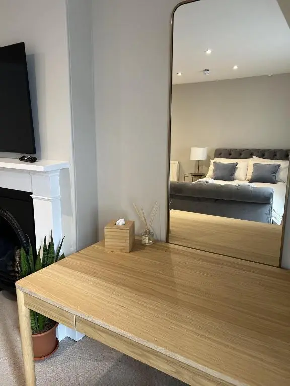 a mirror in a room with a bed and a table at No. Ten Guesthouse in Tain