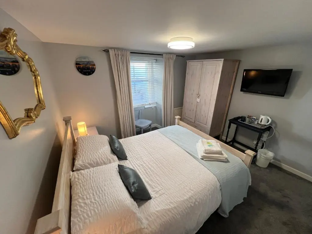 a bedroom with a bed and a mirror and a television at The Garden Arms Pub and Rooms in Gardenstown