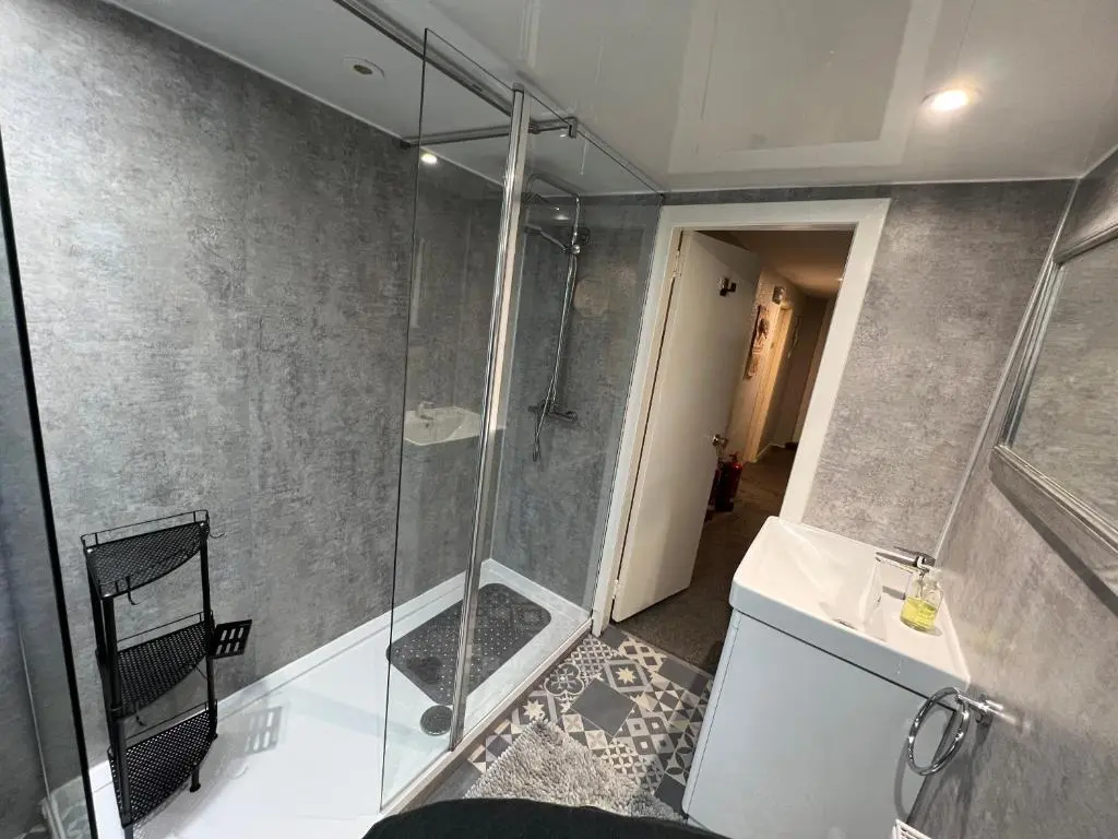 a bathroom with a shower with a glass door at The Garden Arms Pub and Rooms in Gardenstown