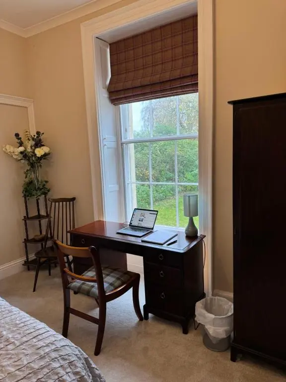 a bedroom with a desk and a window with a laptop on it at Aultnaskiach House Apartment, Inverness in Inverness