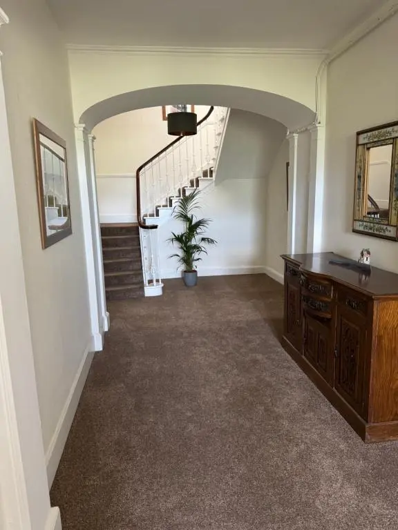 a hallway with a staircase and a table and a potted plant at Aultnaskiach House Apartment, Inverness in Inverness