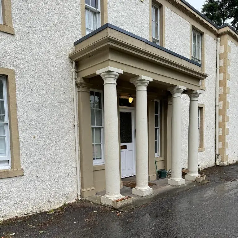 a building with pillars on the front of a door at Aultnaskiach House Apartment, Inverness in Inverness