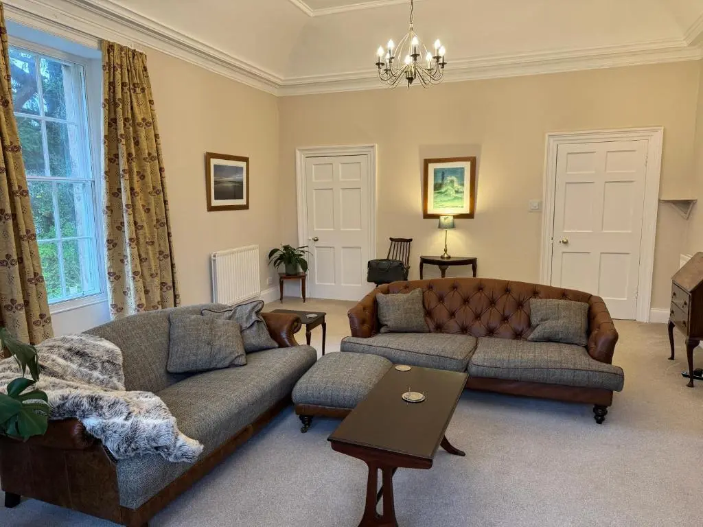 a living room with two couches and a table at Aultnaskiach House Apartment, Inverness in Inverness