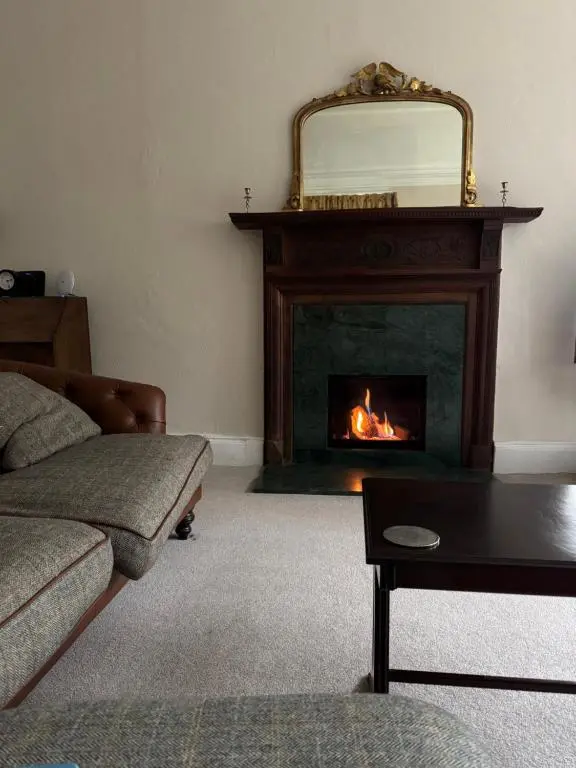 a living room with a fireplace with a mirror at Aultnaskiach House Apartment, Inverness in Inverness