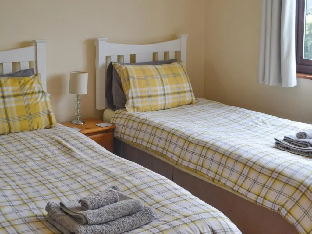 a bedroom with two beds with towels on them at The Junipers in Tain