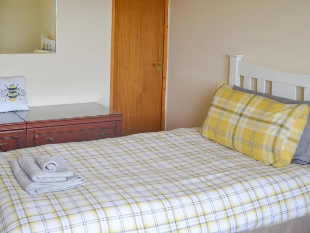 a bedroom with a bed with towels and a pillow at The Junipers in Tain