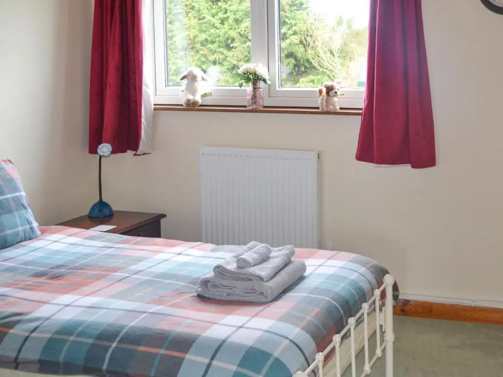 a bedroom with a bed with towels on it at The Junipers in Tain