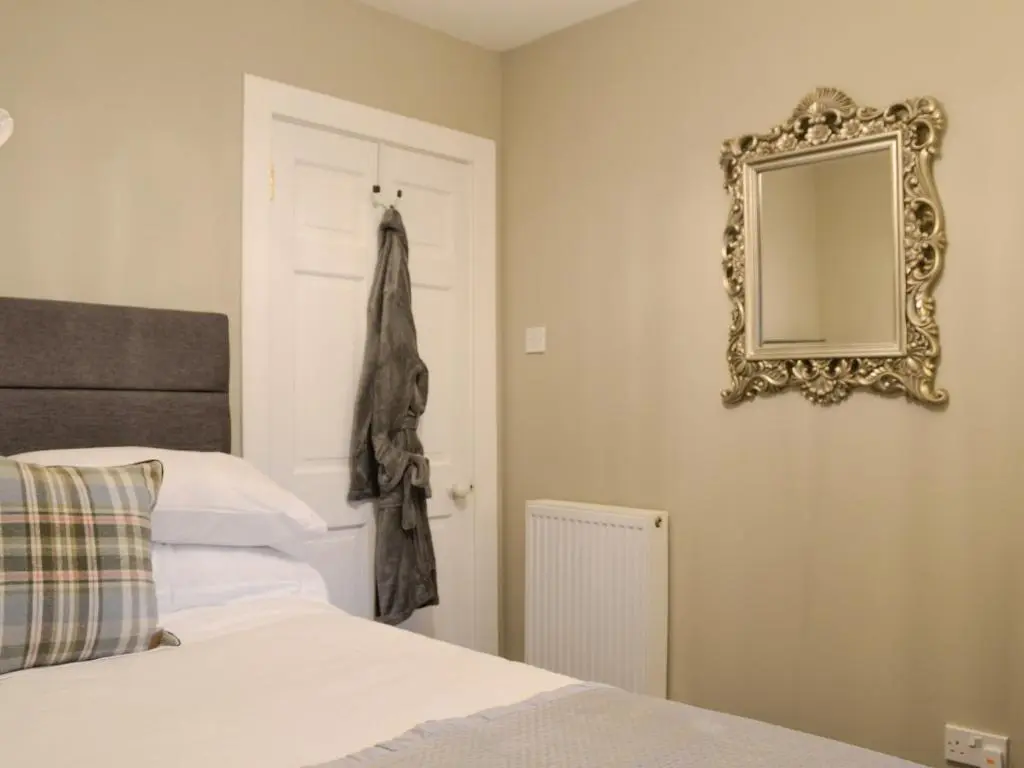 a bedroom with a bed and a mirror on the wall at Logiemar Cottage in Ballater