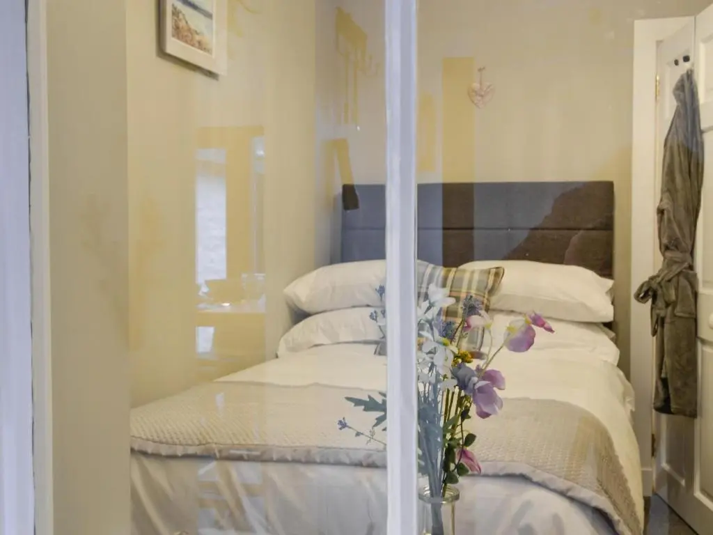 a bedroom with a bed with a mirror at Logiemar Cottage in Ballater