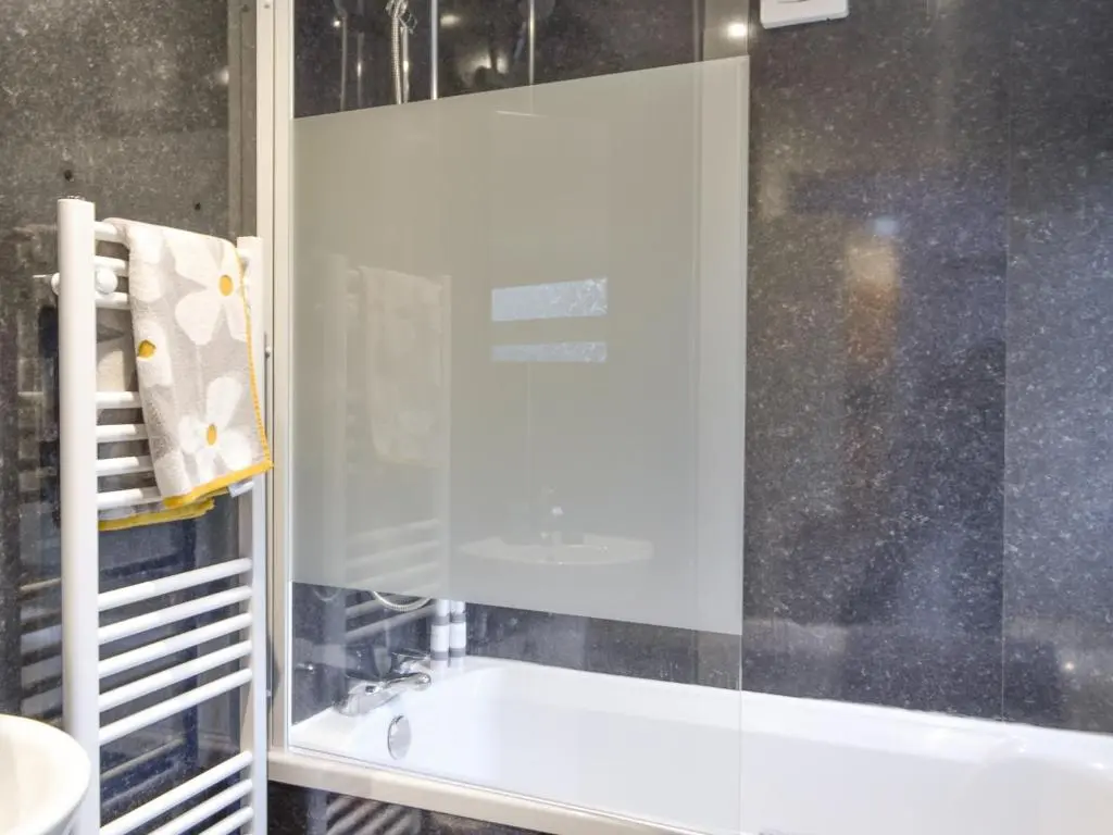 a bathroom with a tub and a glass shower door at Logiemar Cottage in Ballater