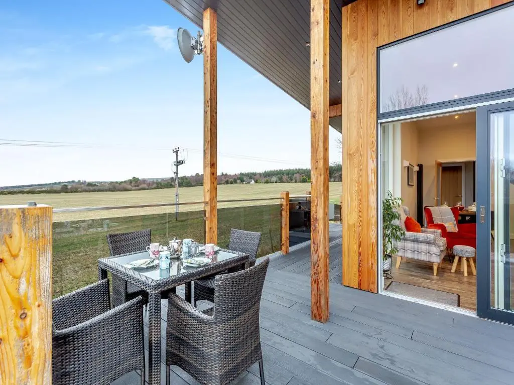 a patio with a table and chairs on a deck at Learag in Culbokie