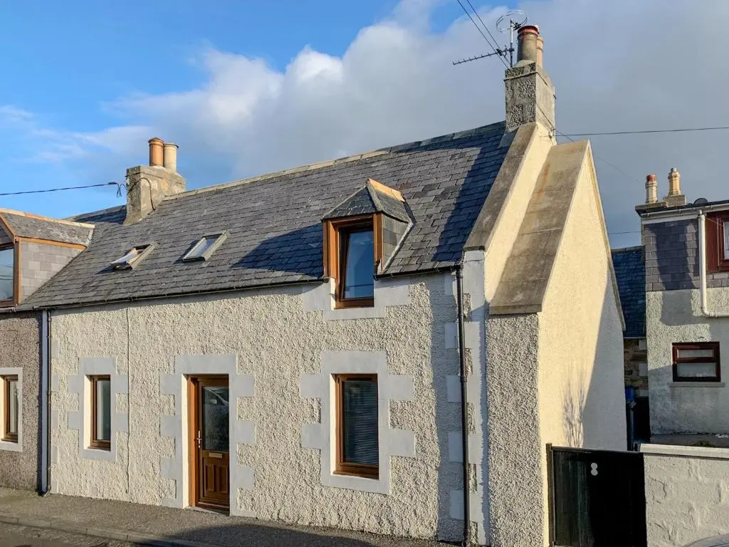 a white house with a gray roof at Seahaven Cottage in Portknockie