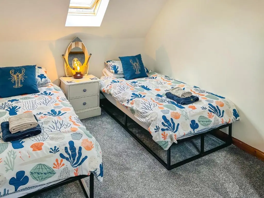 a bedroom with two beds and a mirror at Seahaven Cottage in Portknockie
