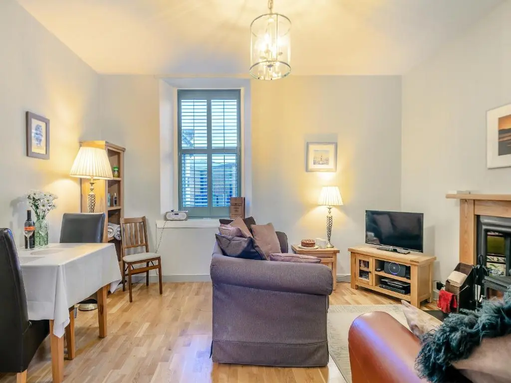 a living room with a couch and a table and a tv at Rowan Cottage in Huntly