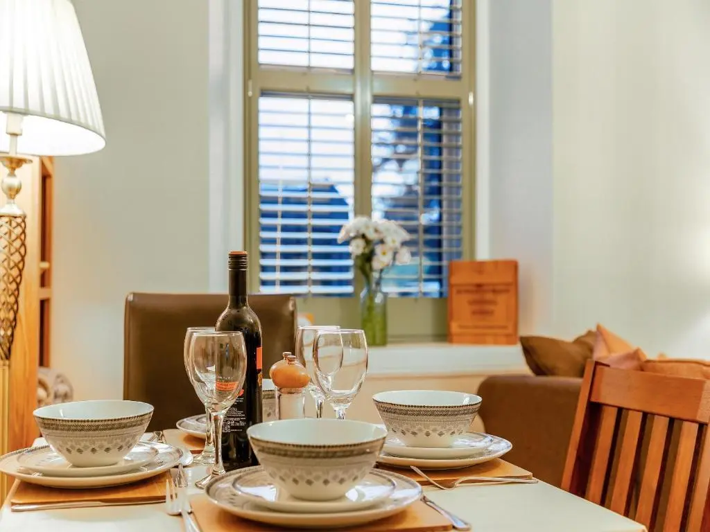 a dining room table with a bottle of wine and glasses at Rowan Cottage in Huntly