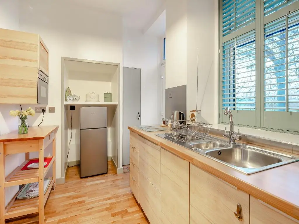 a kitchen with a sink and a refrigerator at Rowan Cottage in Huntly