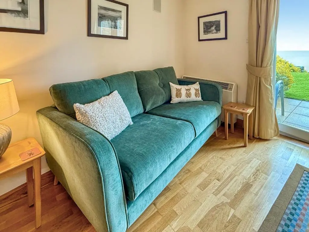 a green couch in a living room with a window at No4 The Links Apartments in Brora