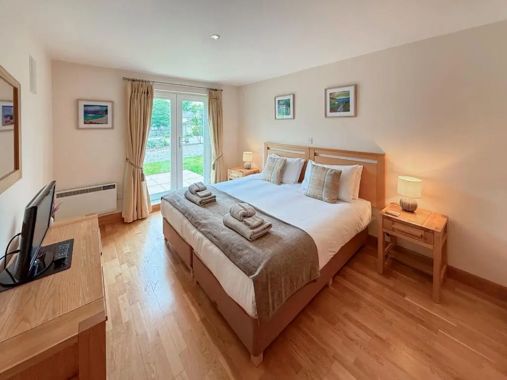 a bedroom with a large bed and a television at No4 The Links Apartments in Brora