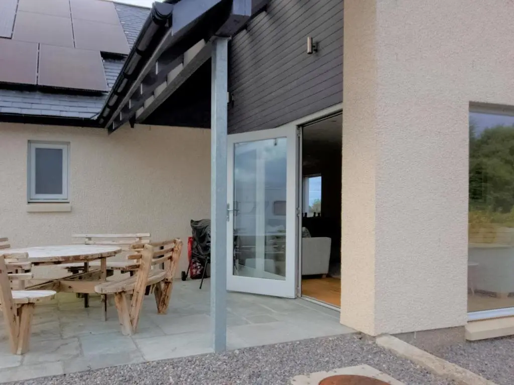 a patio with a table and chairs and a glass door at Darna House in Tain