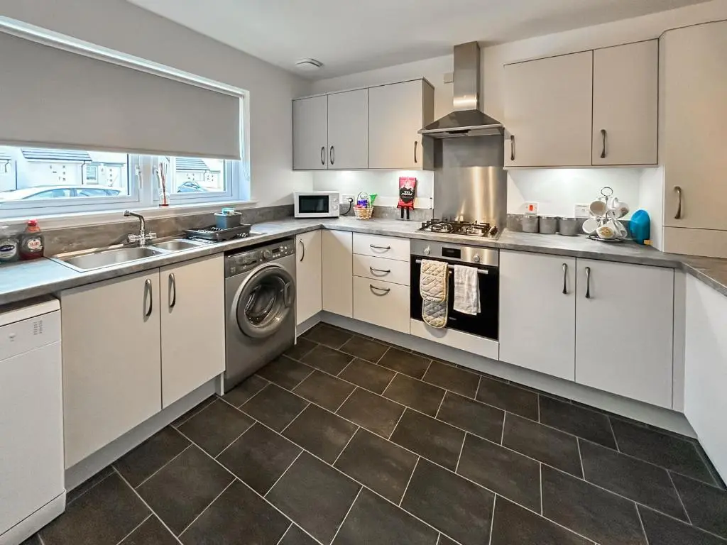 a kitchen with white cabinets and a washer and dryer at Faillie in Inverness