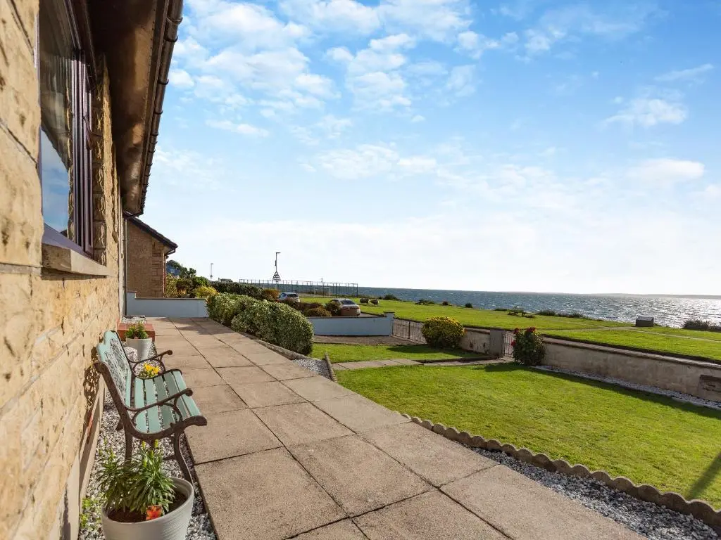 a bench sitting on a balcony looking out at the ocean at Mermaid View in Balintore