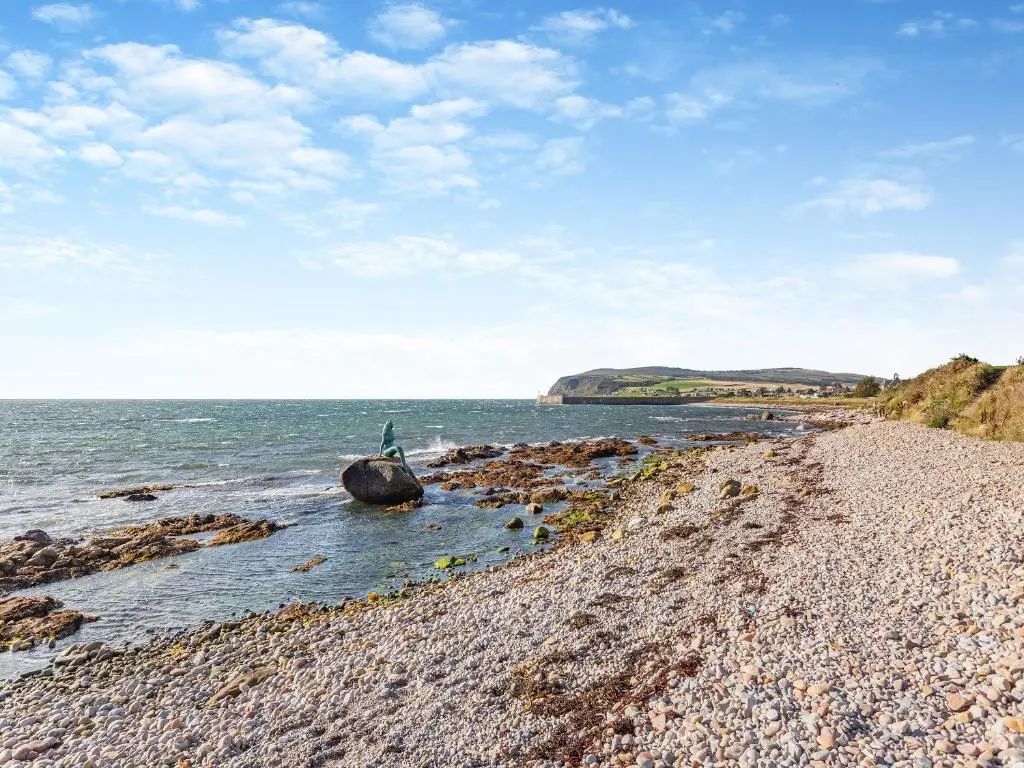 a person sitting on a rock on the beach at Mermaid View in Balintore