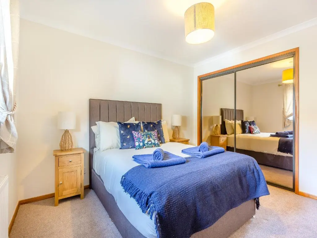 a bedroom with a bed with two blue pillows on it at Mermaid View in Balintore