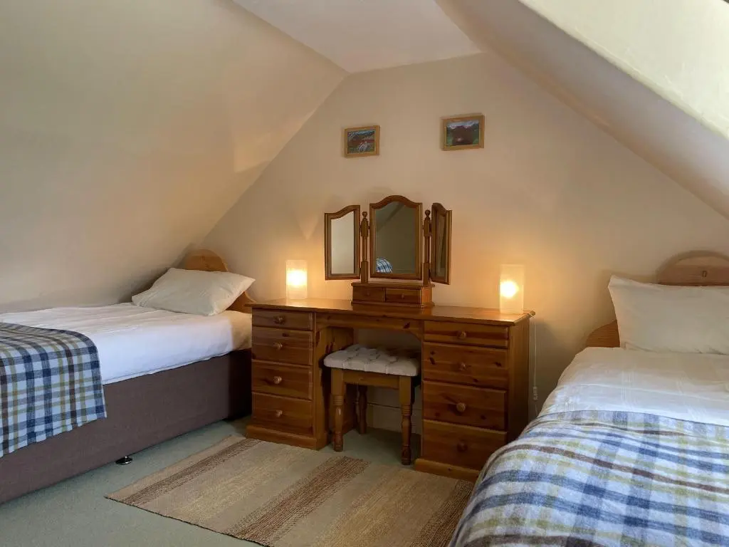 two beds in a room with a mirror and a dresser at Pine Cottage - Dalcross in Dalcross