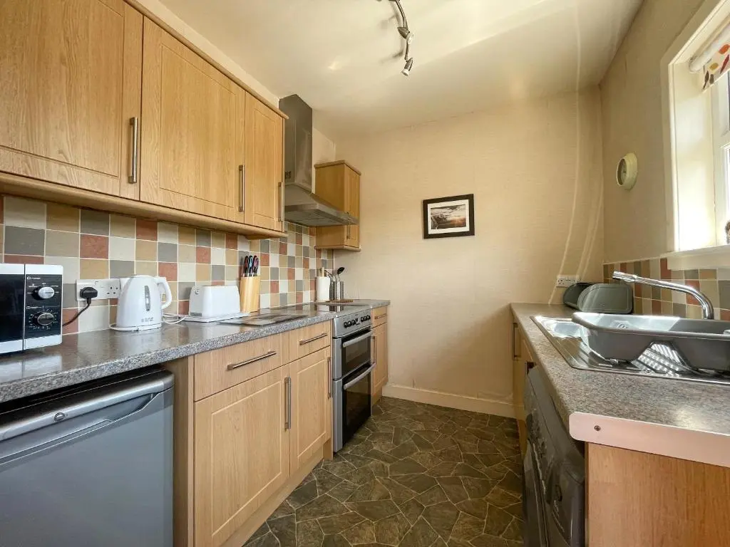 a kitchen with wooden cabinets and a sink at Pine Cottage - Dalcross in Dalcross