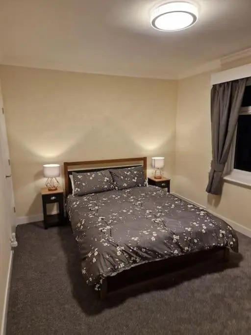 a bedroom with a bed and two lamps and a television at Catalina - Modern 2 bedroom bungalow in Elgin
