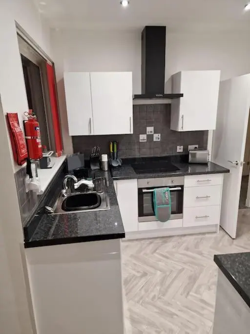 a kitchen with white cabinets and a black counter top at Catalina - Modern 2 bedroom bungalow in Elgin