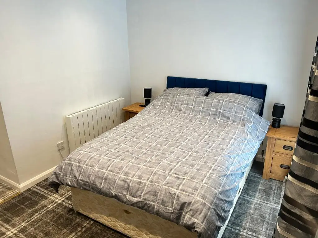 a bedroom with a bed with a plaid blanket at One bed and bathroom with kitchen for self catering Alness in Alness