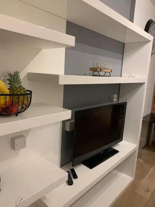 a living room with white shelves with a flat screen tv at Luxury studio flat in a coastal town of Nairn in Nairn