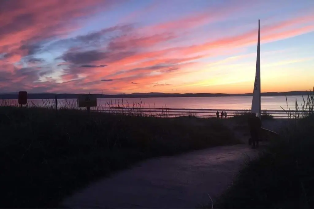 a person walking down a path in front of a sunset at Luxury studio flat in a coastal town of Nairn in Nairn