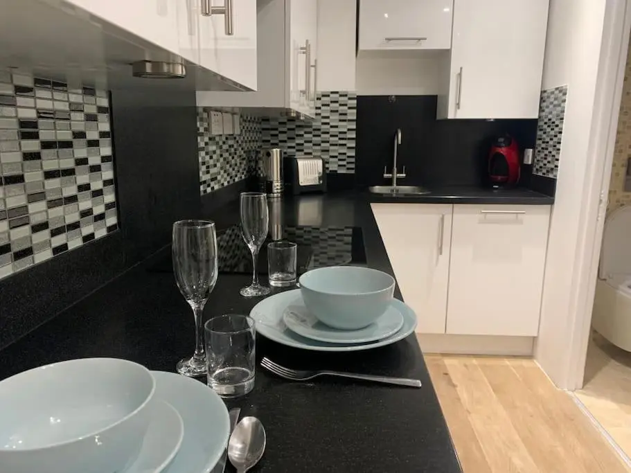 a kitchen with a table with plates and wine glasses at Luxury studio flat in a coastal town of Nairn in Nairn