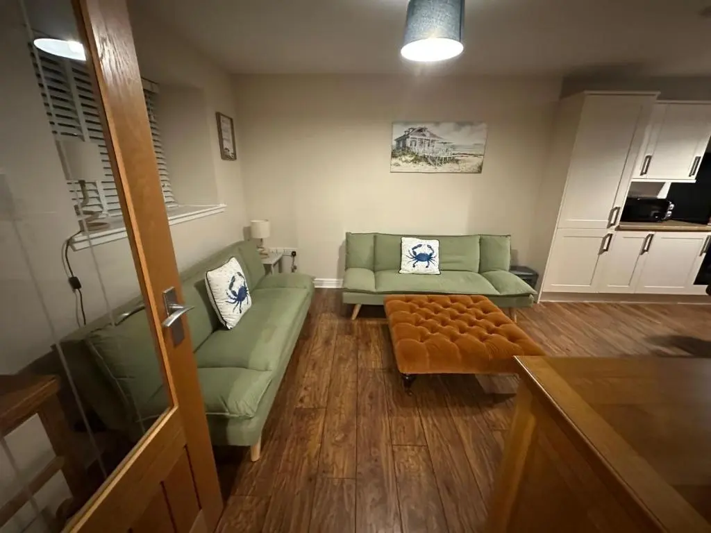 a living room with two green chairs and a couch at Pebble Cottage in Golspie