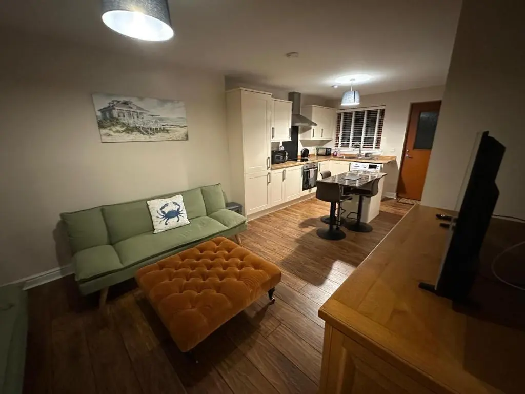 a living room with a green couch and a stool at Pebble Cottage in Golspie