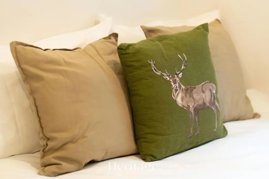 a deer applique on a green pillow on a couch at The Stables Cottage, Aboyne, Peaceful Stay in Royal Deeside in Aboyne