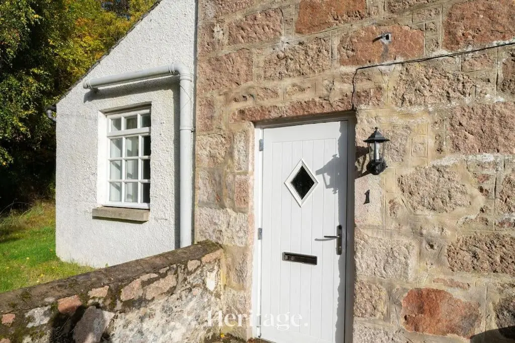 a stone building with a white door and a window at The Stables Cottage, Aboyne, Peaceful Stay in Royal Deeside in Aboyne