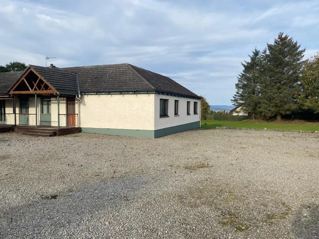 a small house with a gravel parking lot at Carnegie Lodgings, Tain in Tain