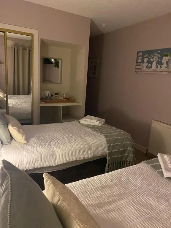 a hotel room with two beds and a mirror at Carnegie Lodgings, Tain in Tain