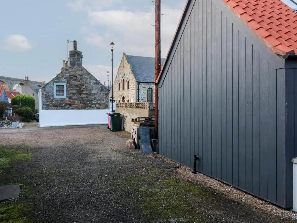 a building with a fence next to a house at 171 Seatown in Buckie