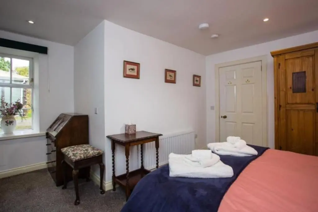 a bedroom with two beds and a desk and a window at The Garden Flat - Ardullie Lodge in Dingwall