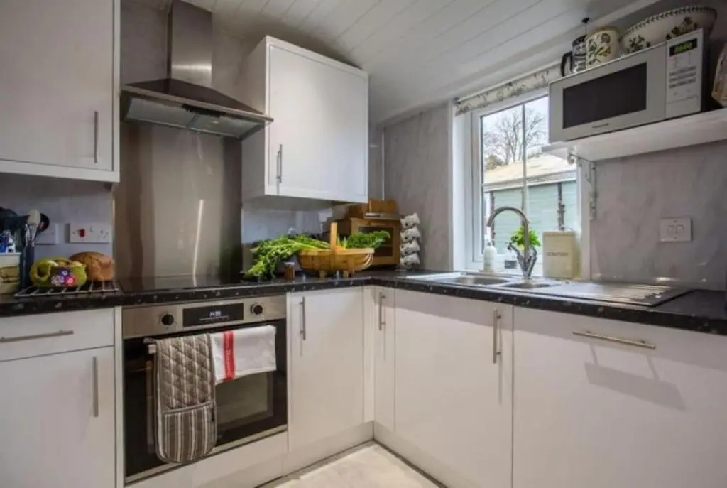 a kitchen with white cabinets and a stove top oven at The Garden Flat - Ardullie Lodge in Dingwall