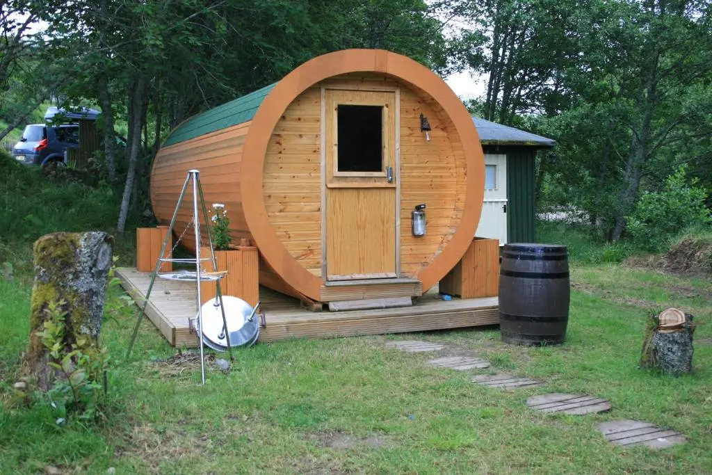 a large wooden cabin with a door in a yard at BCC Lochness Hostel pods in Bearnock