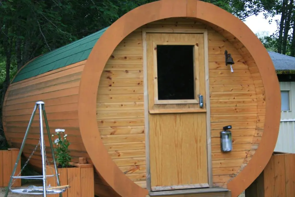a large wooden hobbit house with a round door at BCC Lochness Hostel pods in Bearnock