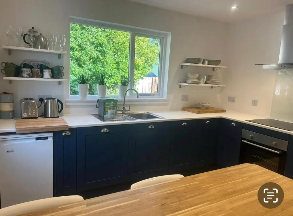 a kitchen with blue cabinets and a sink and a window at Balmanach Court in Beauly