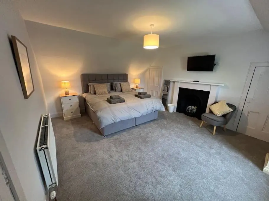 a bedroom with a bed and a fireplace and a television at 1 Links Place in Nairn